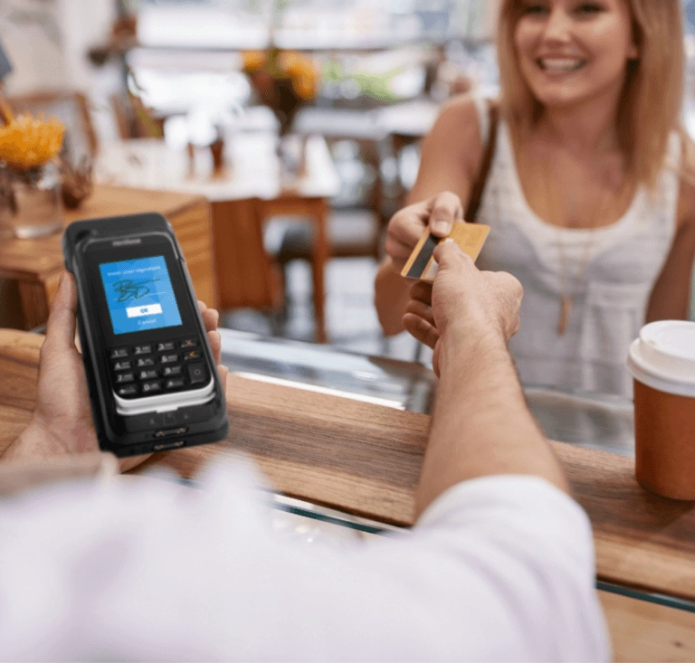 Donna che consegna la carta di credito a un addetto che tiene in mano un mPOS