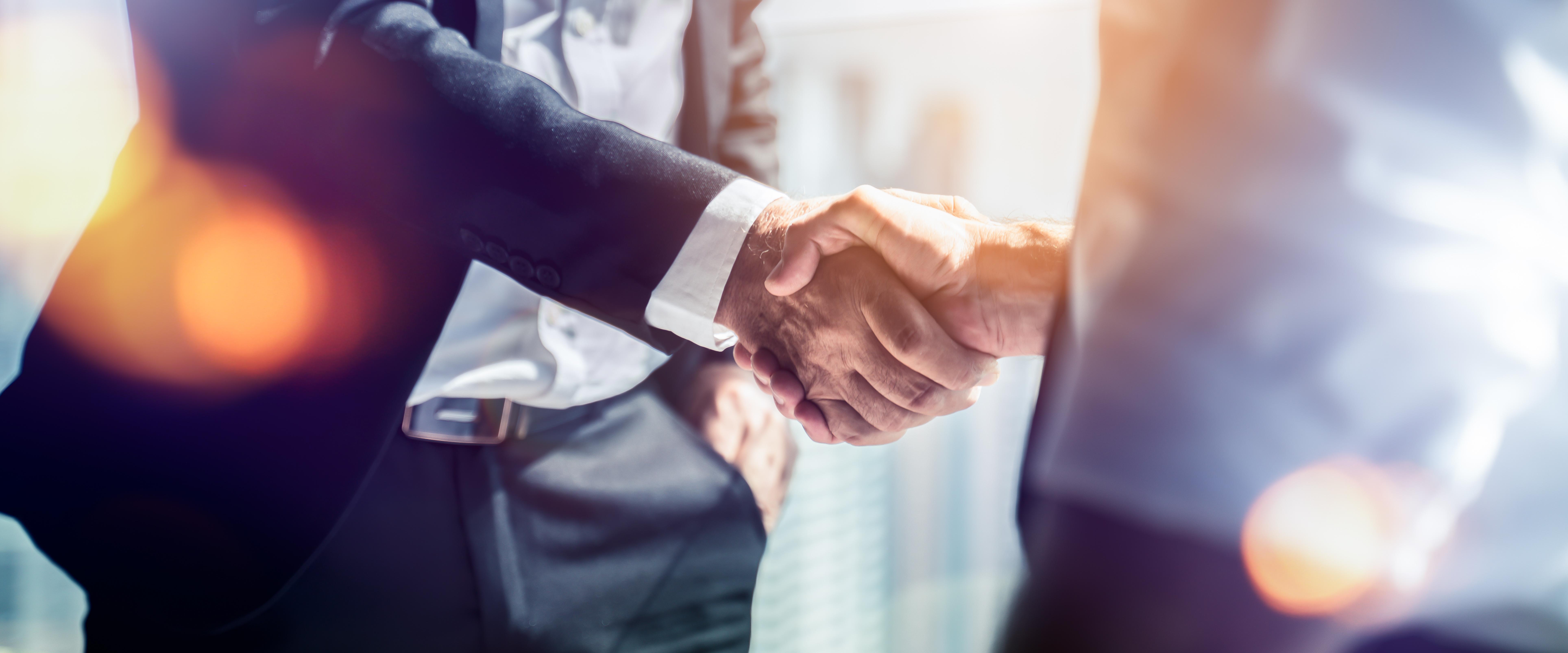 Stretta di mano tra uomini d'affari per celebrare la collaborazione in materia di fusioni e acquisizioni aziendali, negoziazioni riuscite, stretta di mano, due uomini d'affari stringono la mano al partner per festeggiare la partnership e l'accordo commerciale.