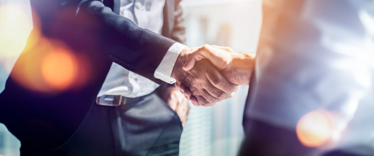 Stretta di mano tra uomini d'affari per celebrare la collaborazione in materia di fusioni e acquisizioni aziendali, negoziazioni riuscite, stretta di mano, due uomini d'affari stringono la mano al partner per festeggiare la partnership e l'accordo commerciale.